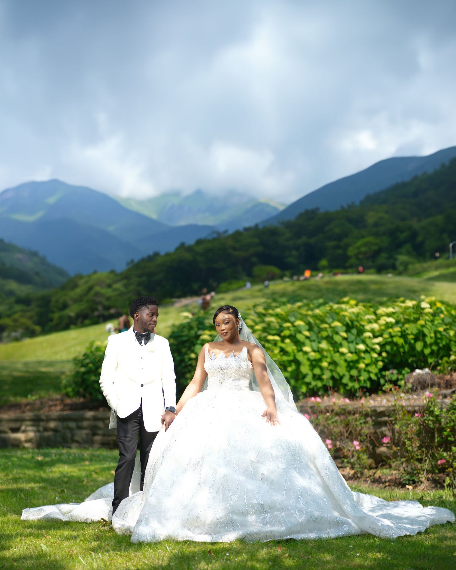 Couple on a hillside lawn with mountains behind them