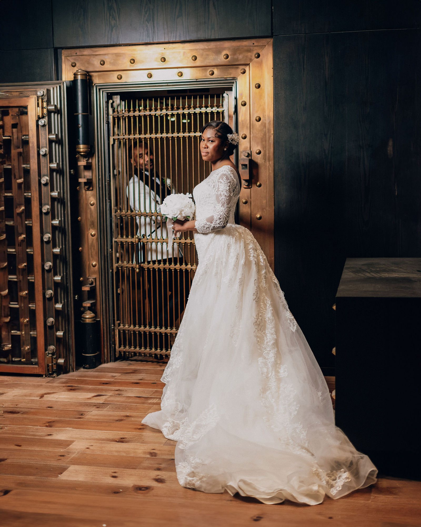 Bride in a ball gown beside a brass bank-vault door