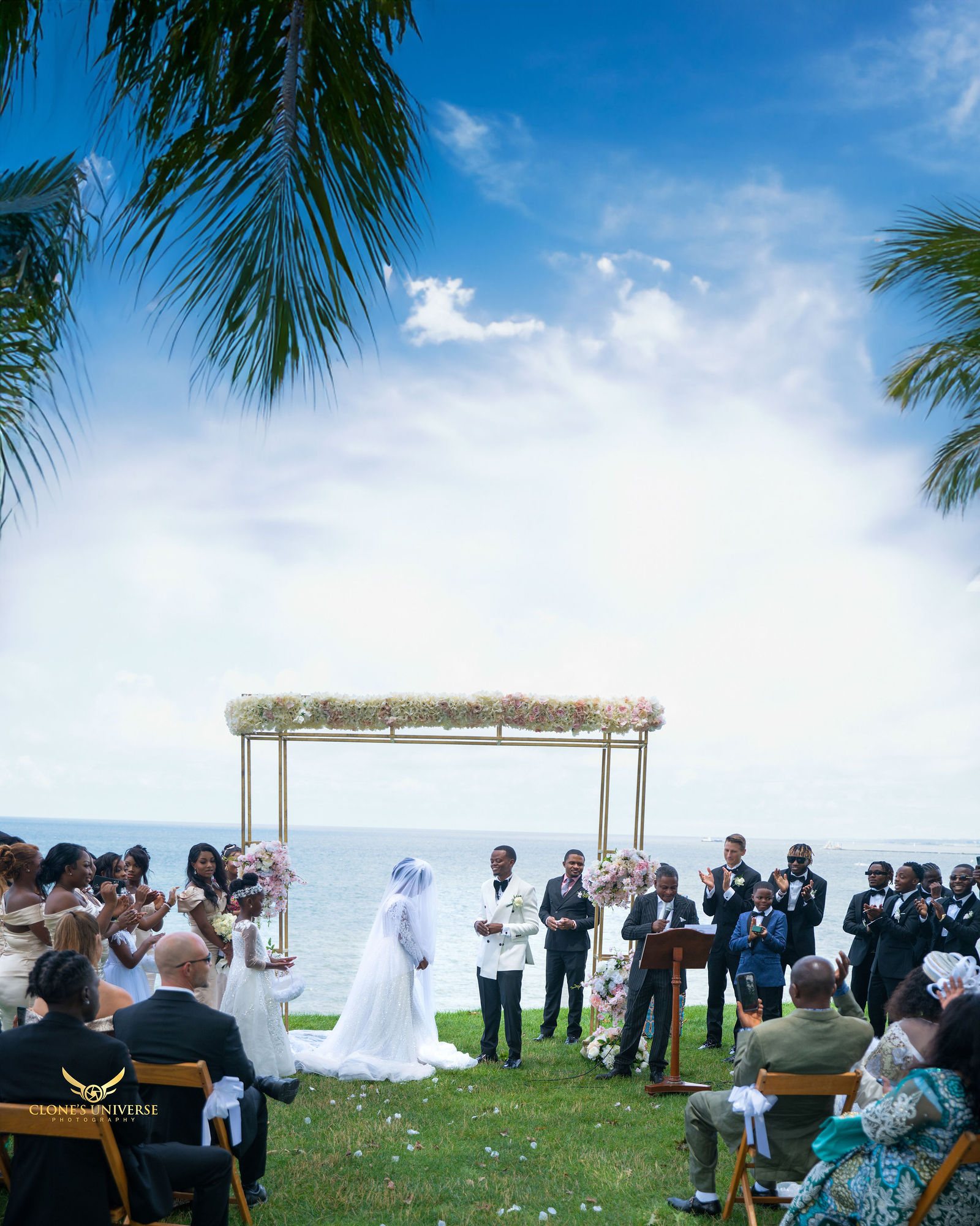 Waterfront ceremony under palm trees and a blue sky