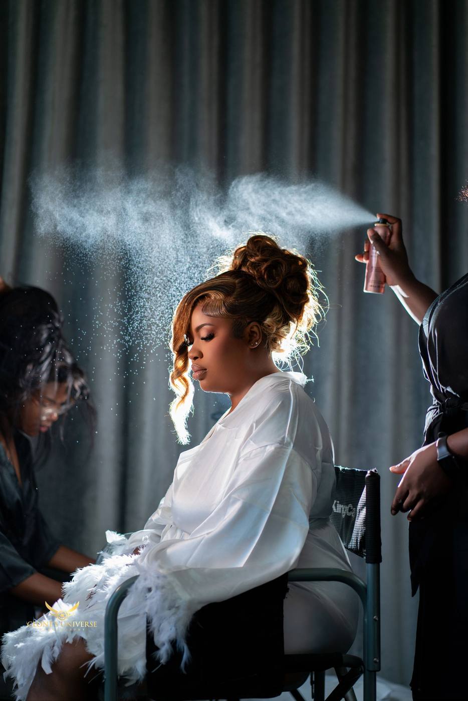 Bride having her hair set, spray catching the backlight