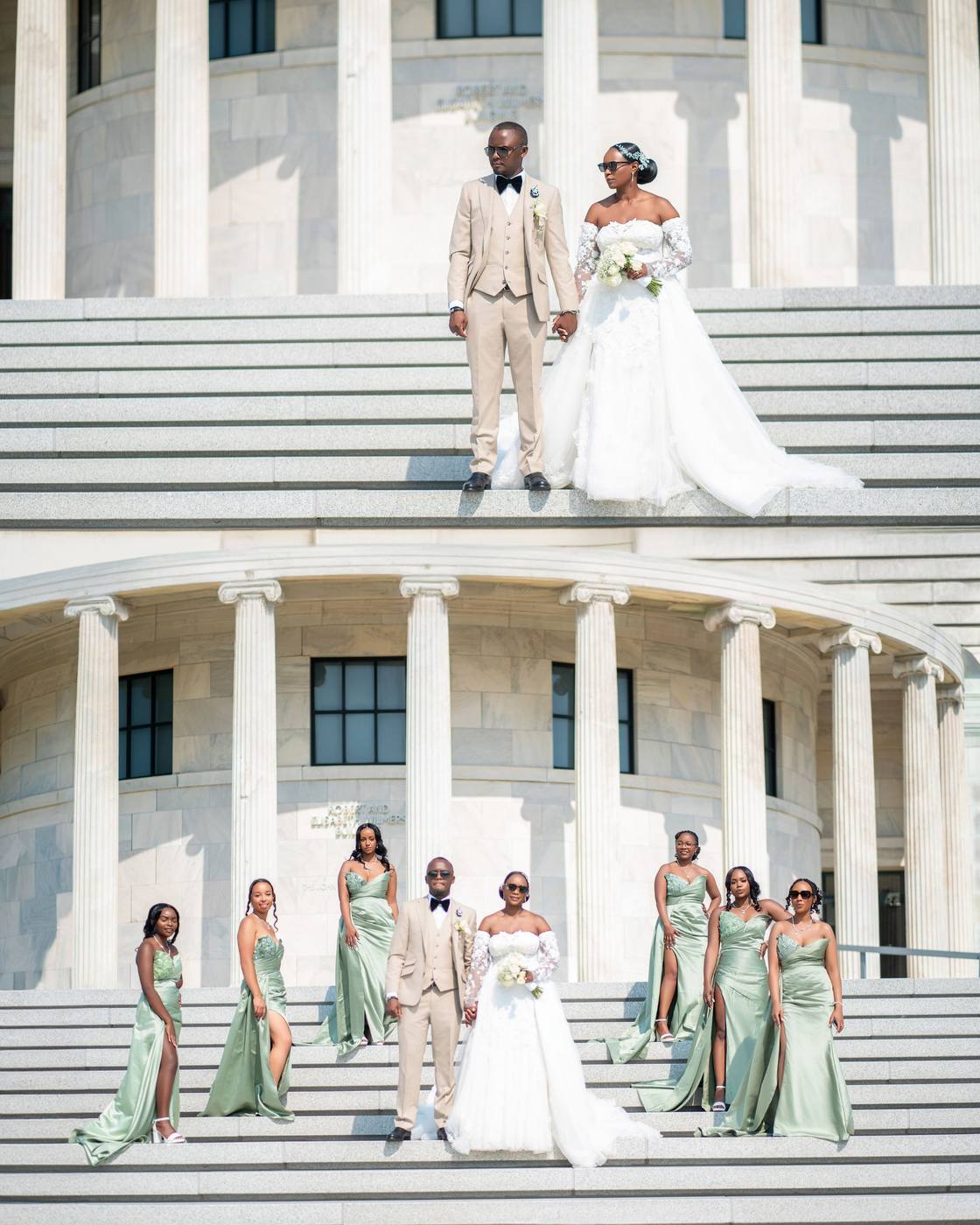 Couple and bridesmaids in sage green on marble steps